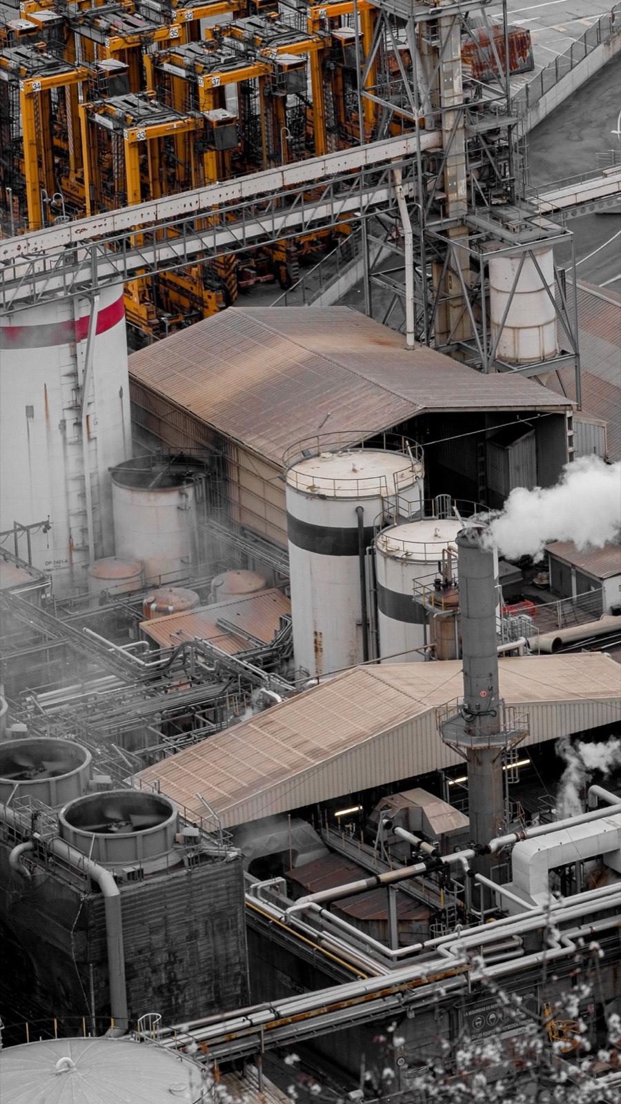 Industrial processing plant, storage tanks and stacks venting steam.